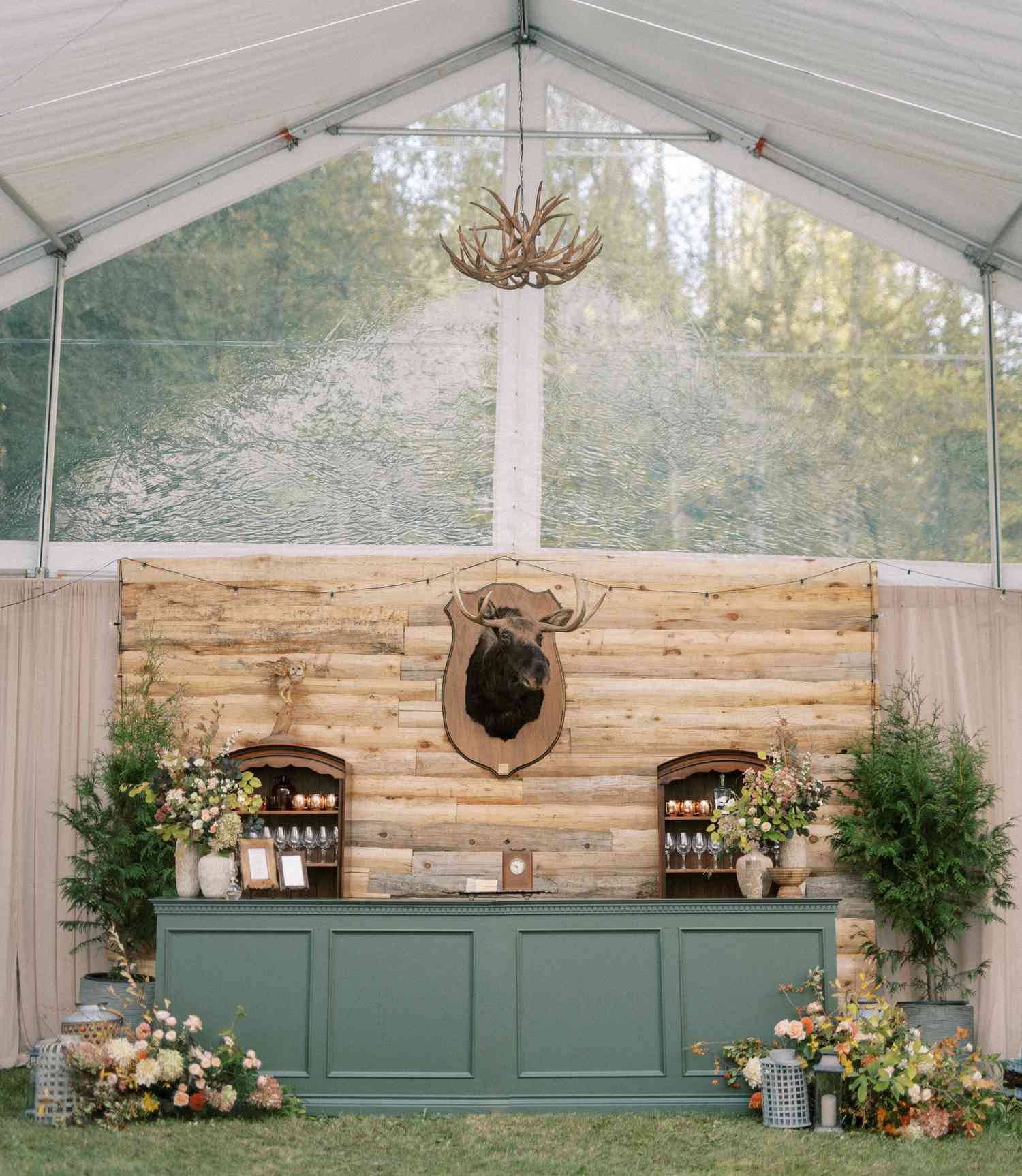 Green Wedding Bar With Wood Backdrop With Moose and Antler Chandelier Overhead
