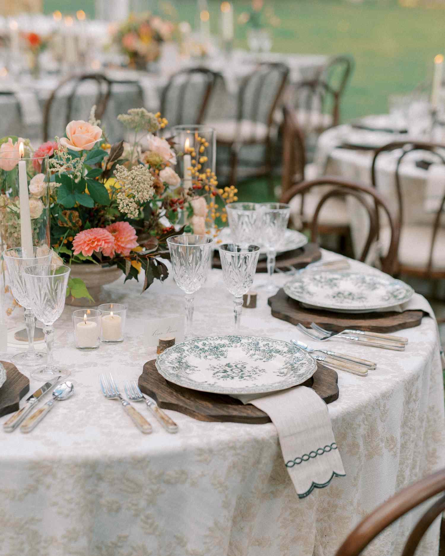 Green and White Plates on Wooden Boards for Table Setting Next to Colorful Flower Decor at Reception