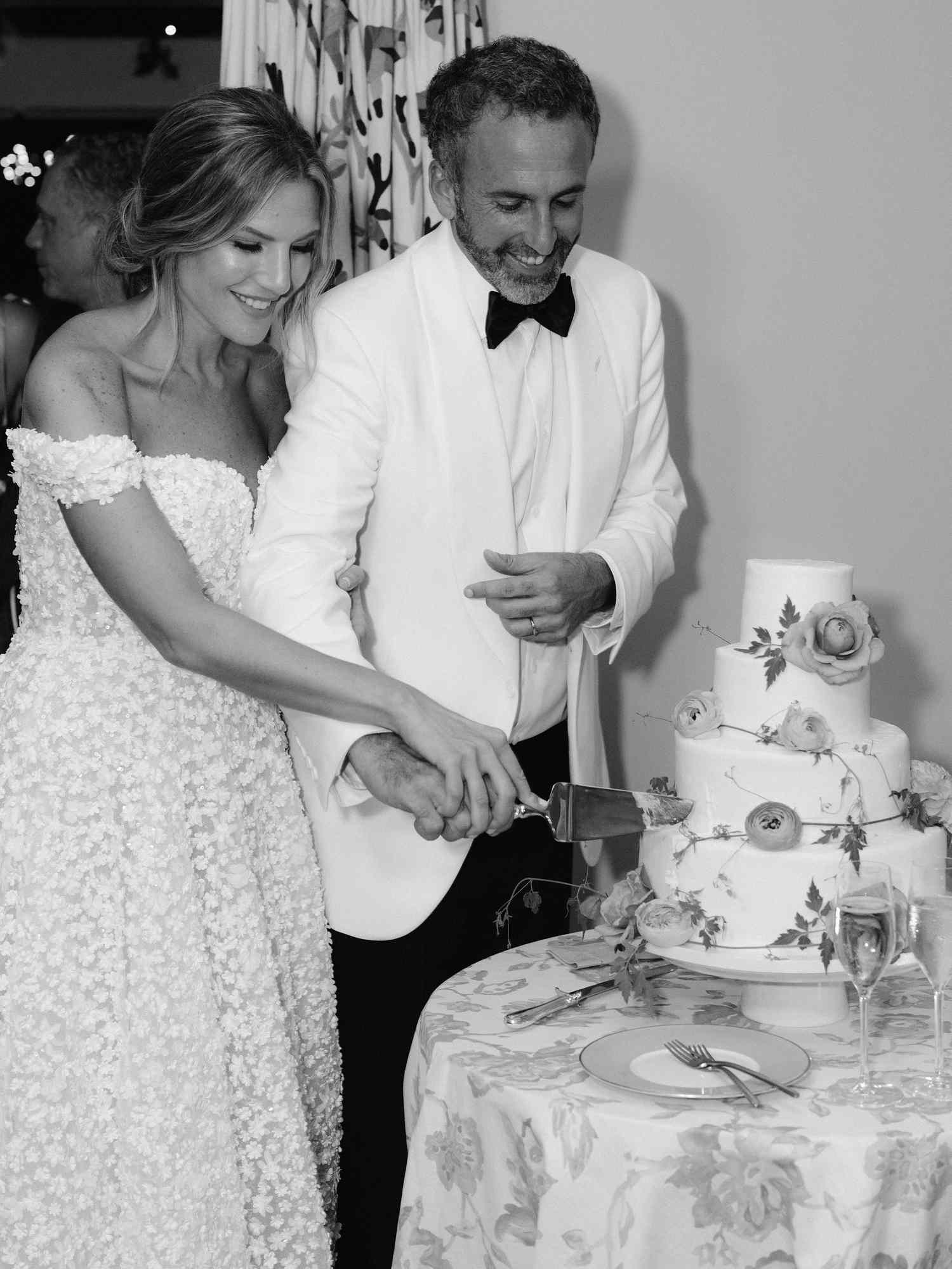 black and white photo of bride and groom cutting wedding cake