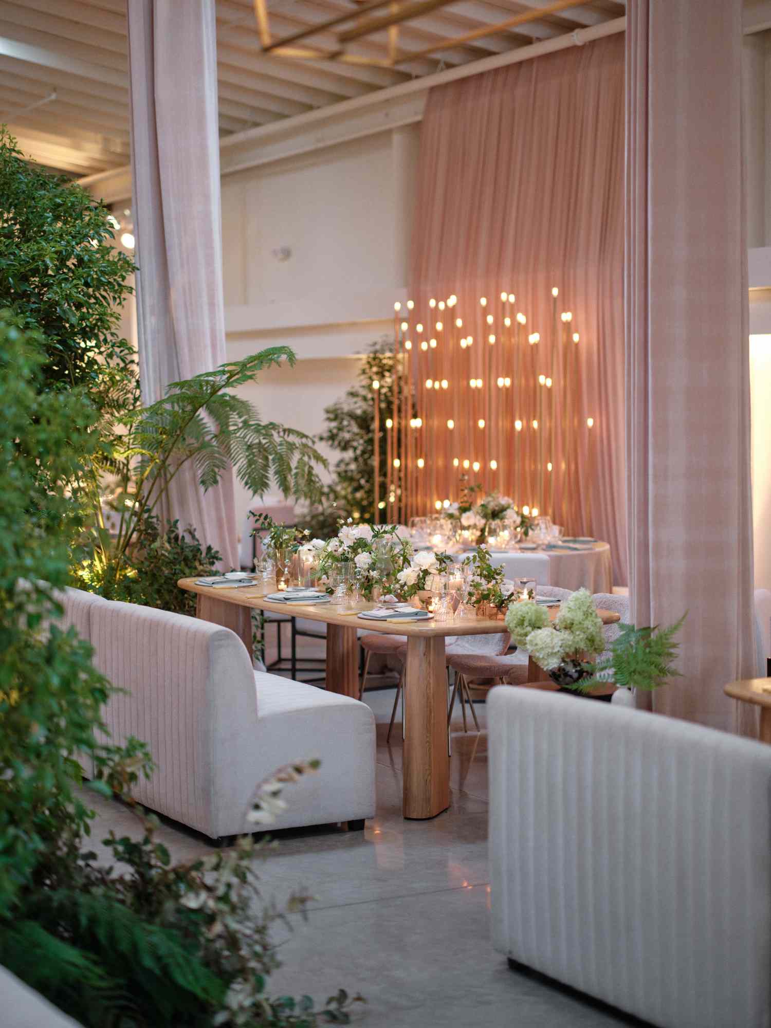 Reception Tables With White Chairs and White Flower, Plant, and Candle Decor By Nude Curtains