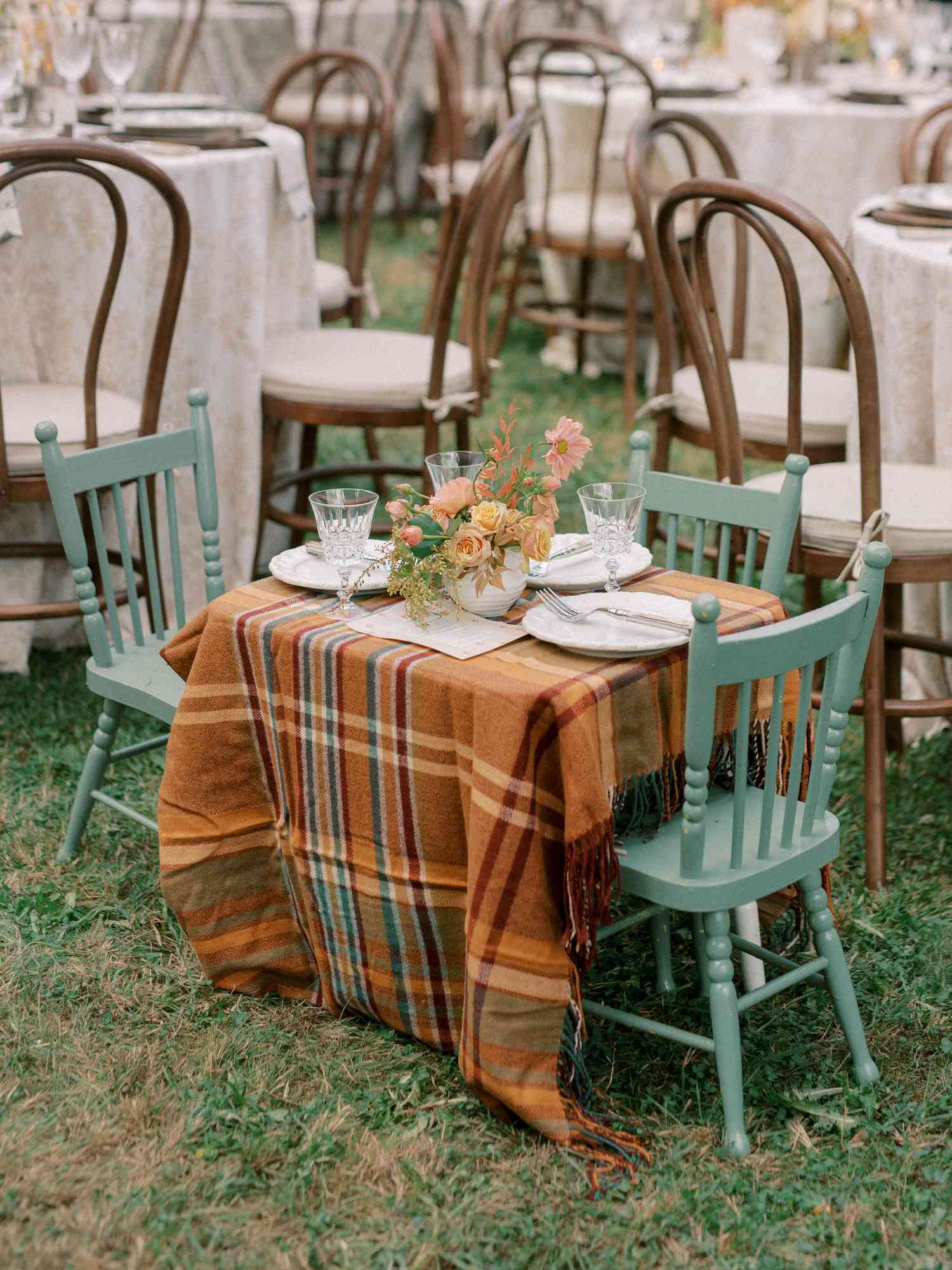 Small Kids Table With Brown Plaid Cloth, Green Chairs, and Colorful Flower Decor