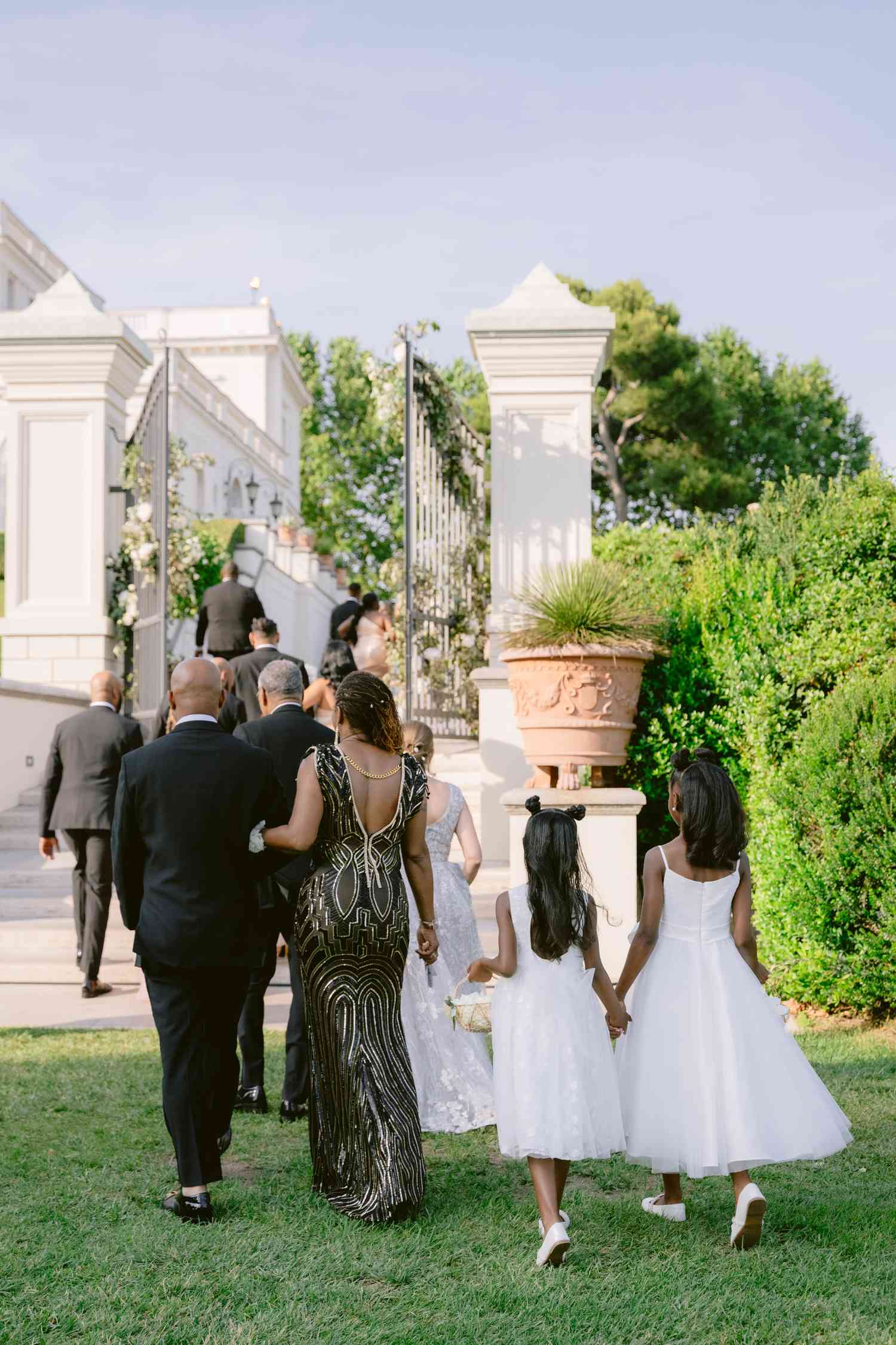 Guests in Black and White Attire Walking Towards Reception in White Villa