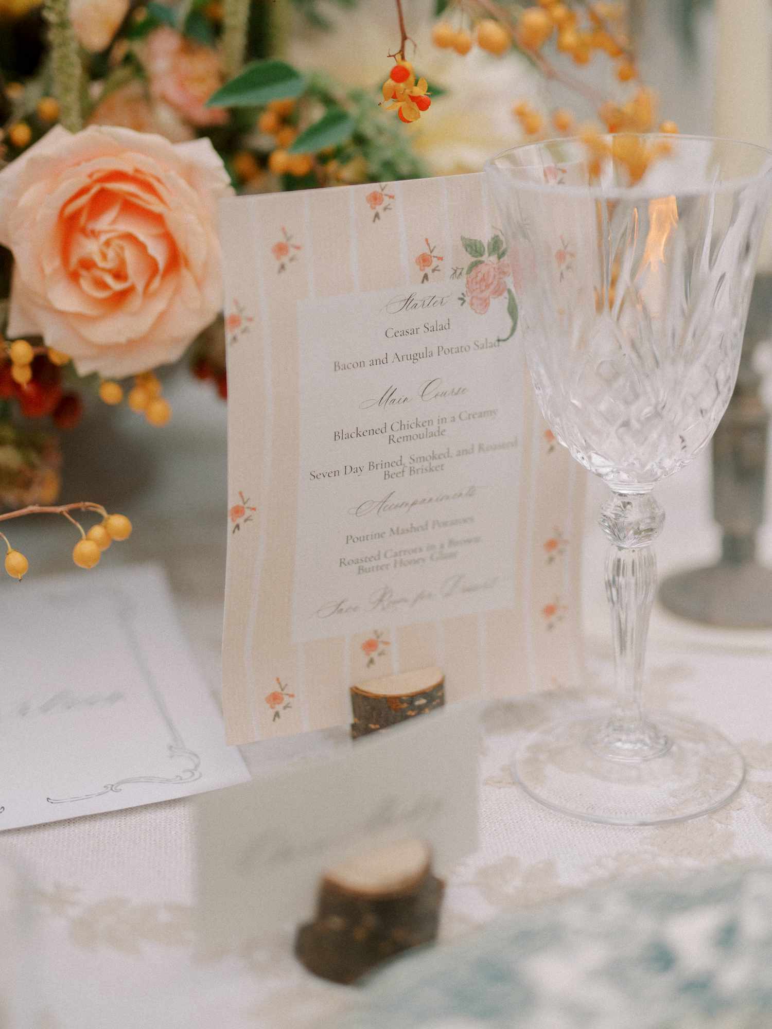 Floral Entree Menu Next to Flower Decor and Cocktail Glass at Reception