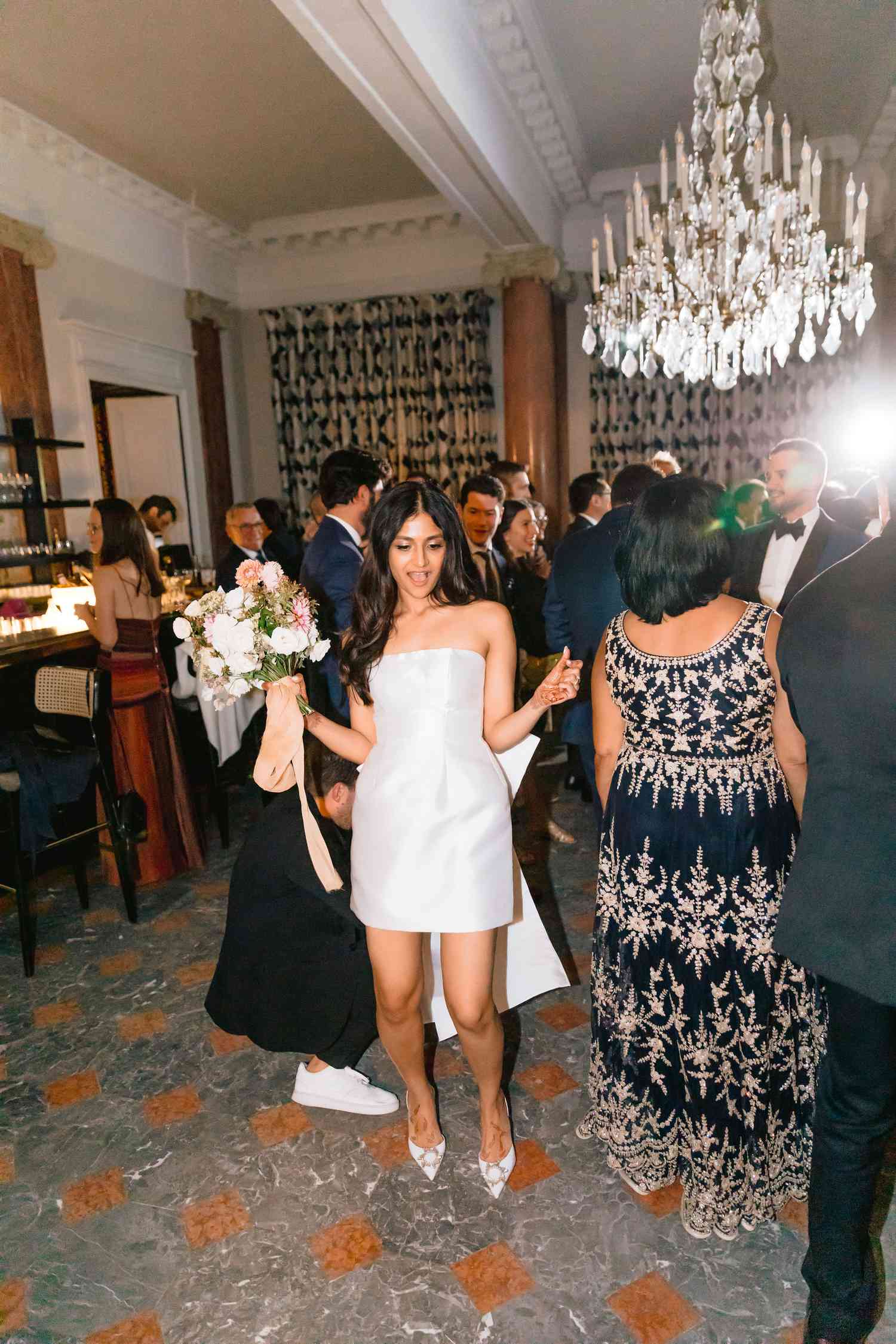 bride in white short wedding dress hold flower bouquet on dance floor