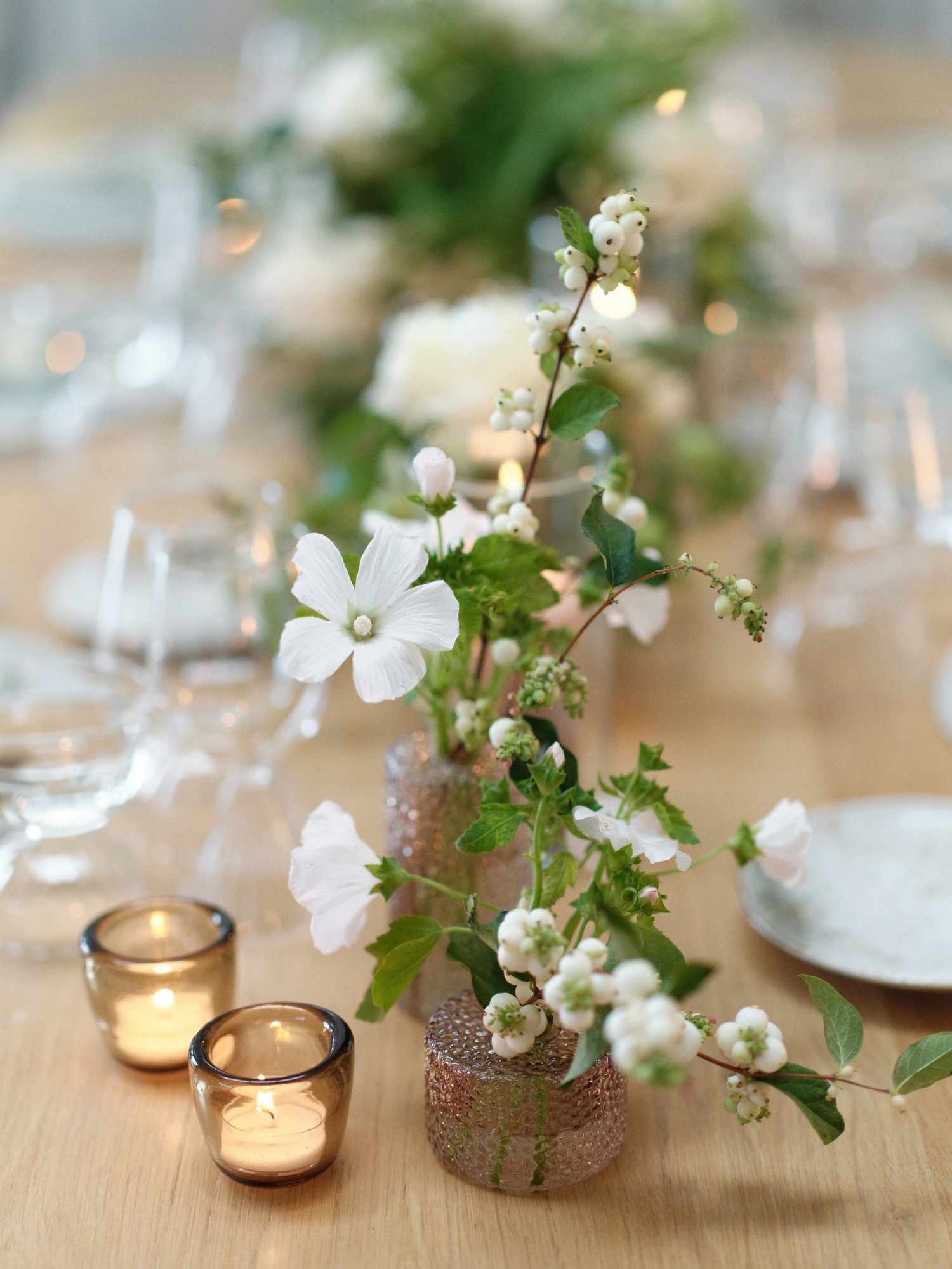 Close Up of White Flower Decor in Small Glass Vase Next to Candles
