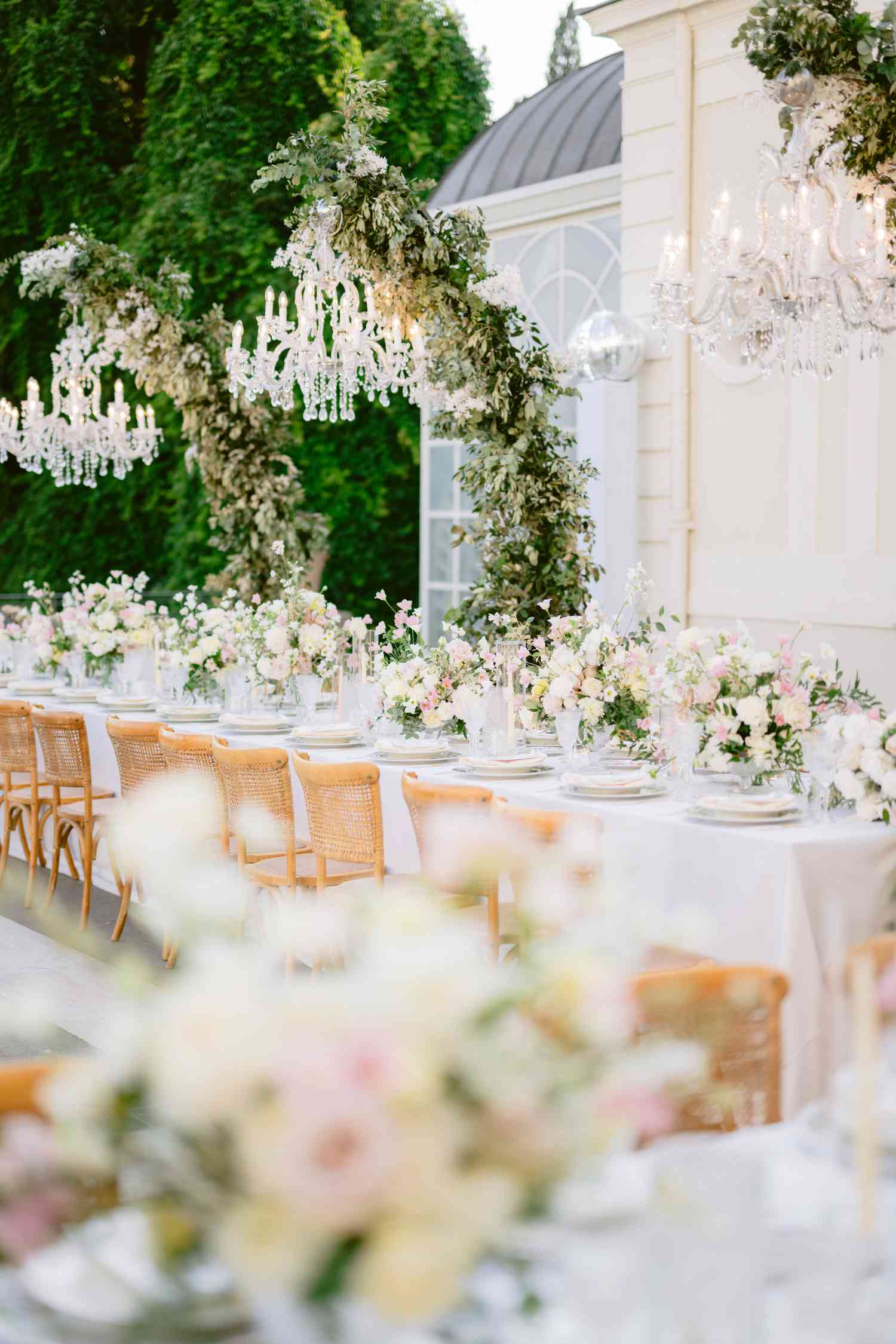 White and Pastel Flower Decor on Reception Tables With Chandeliers Hanging Above