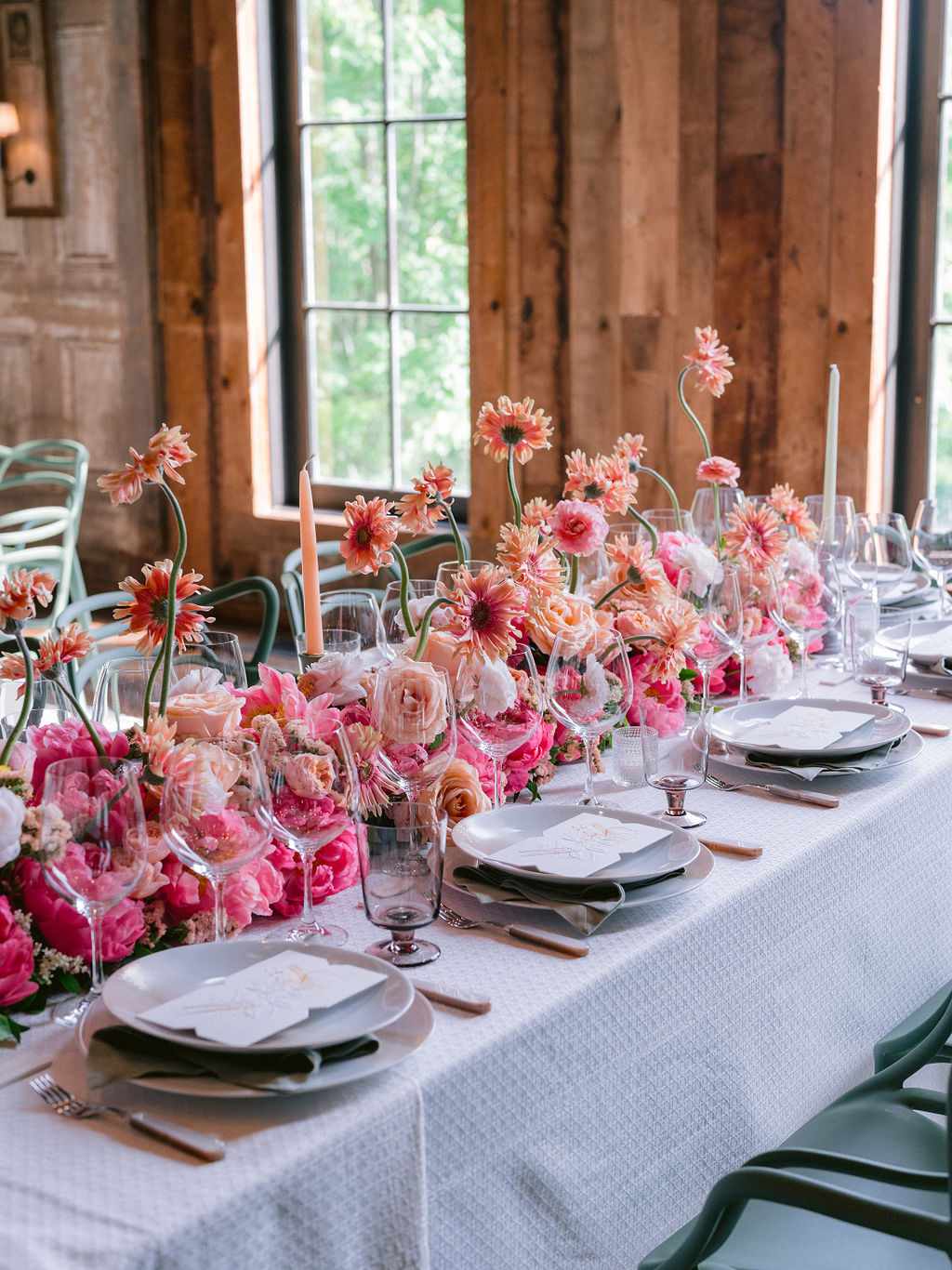 Rustic Indoor Wedding Reception Space with Lush Pink Centerpieces of Peonies, Gerber Daisies, and Roses