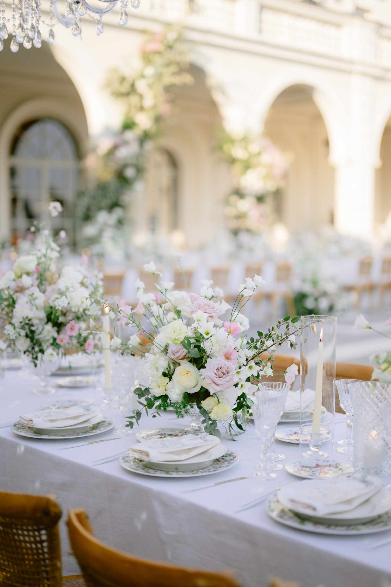 White and Pastel Flower Decor on Reception Tables Next to White Botanical Table Settings and Candles