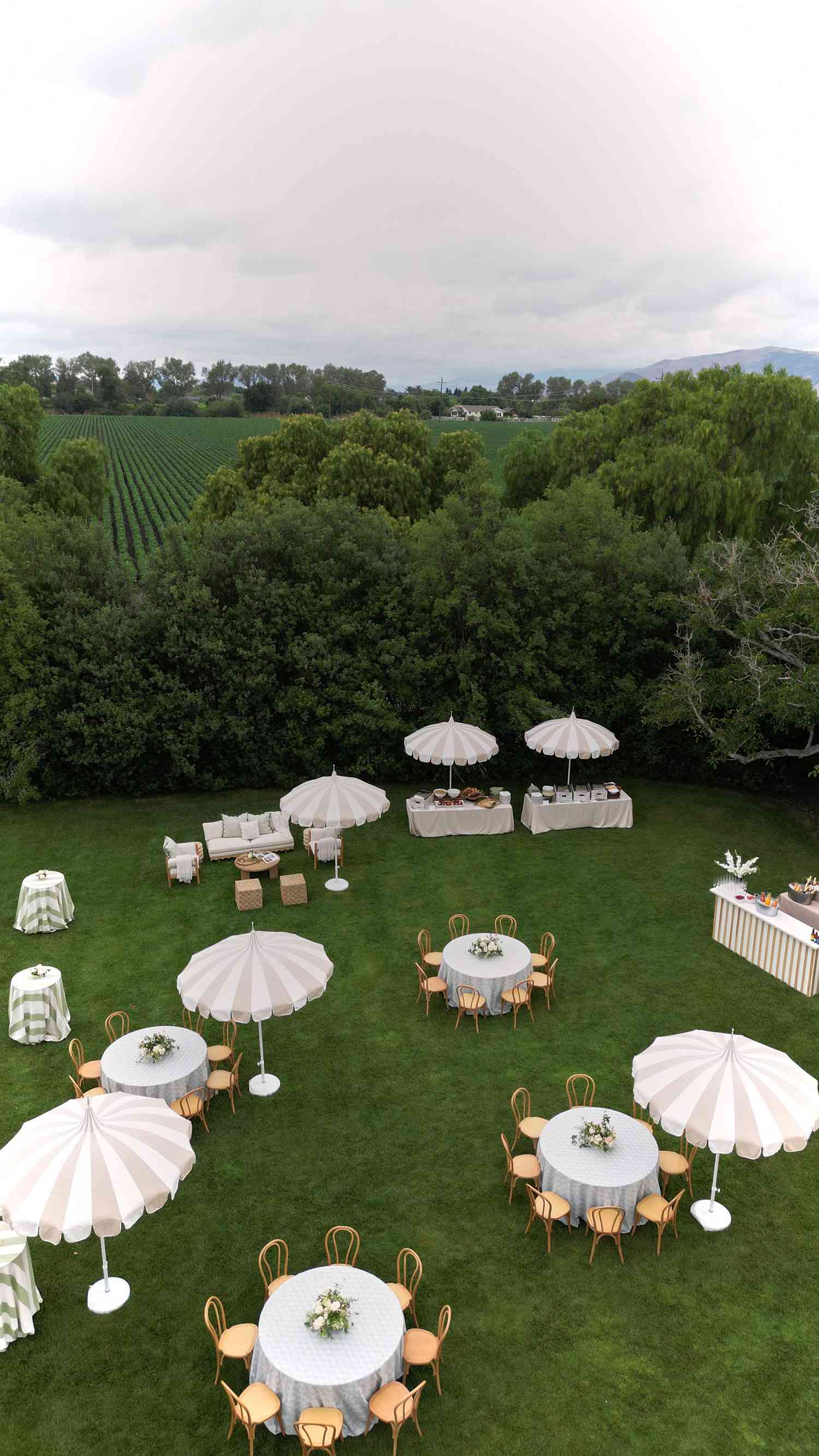 White Round Tables With Stripped Umbrellas in Yard For Day After Wedding Party