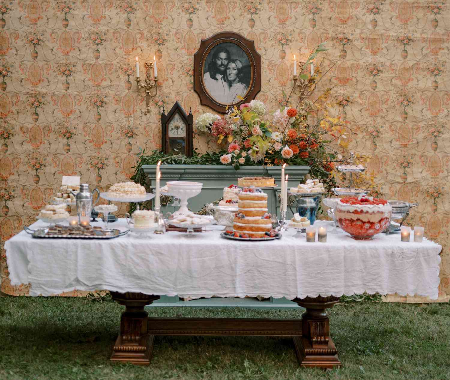 Desserts on Farm Table With Fireplace and Colorful Flower Decor Below Couple Picture Frame
