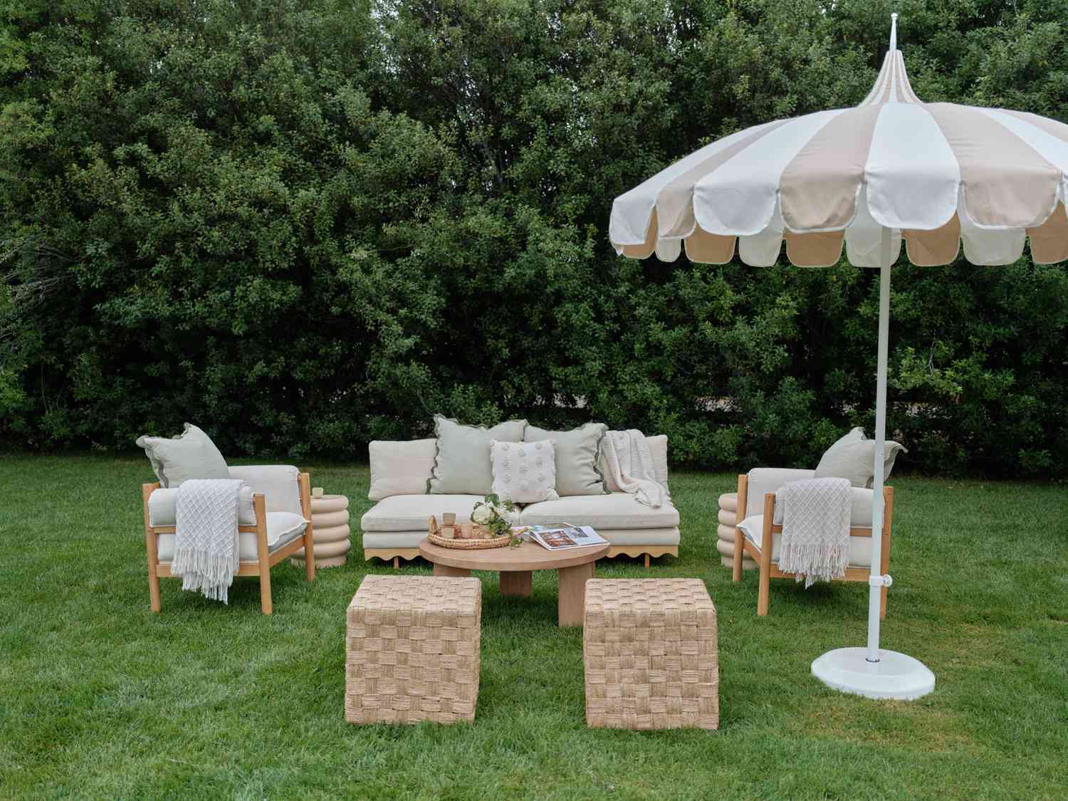 Lounge Area With Muted Green and Tan Couches, Rattan Ottomans, and Stripped Umbrella at Day After Wedding Party
