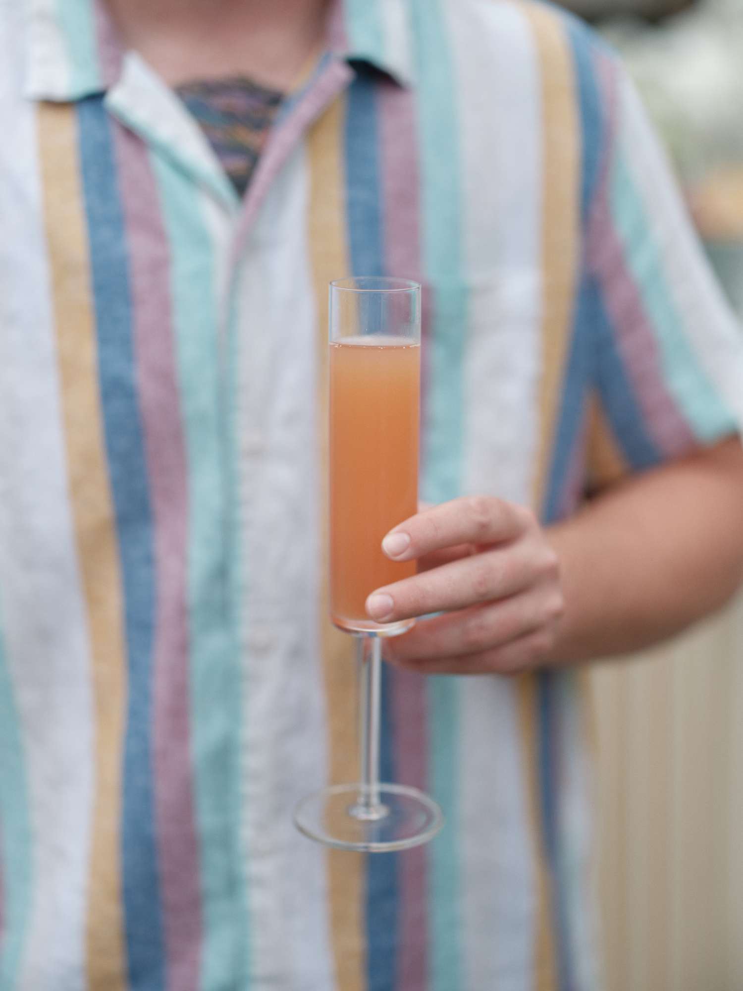 Man in Colorful Stripped Shirt Holding Orange Cocktail at Day After Wedding Party