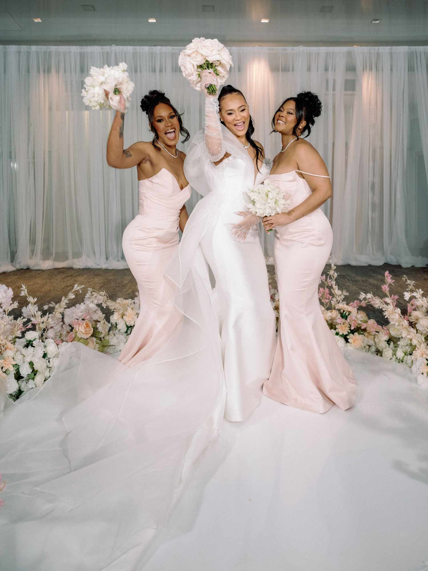 bride and bridesmaids holding flower bouquets dancing and smiling