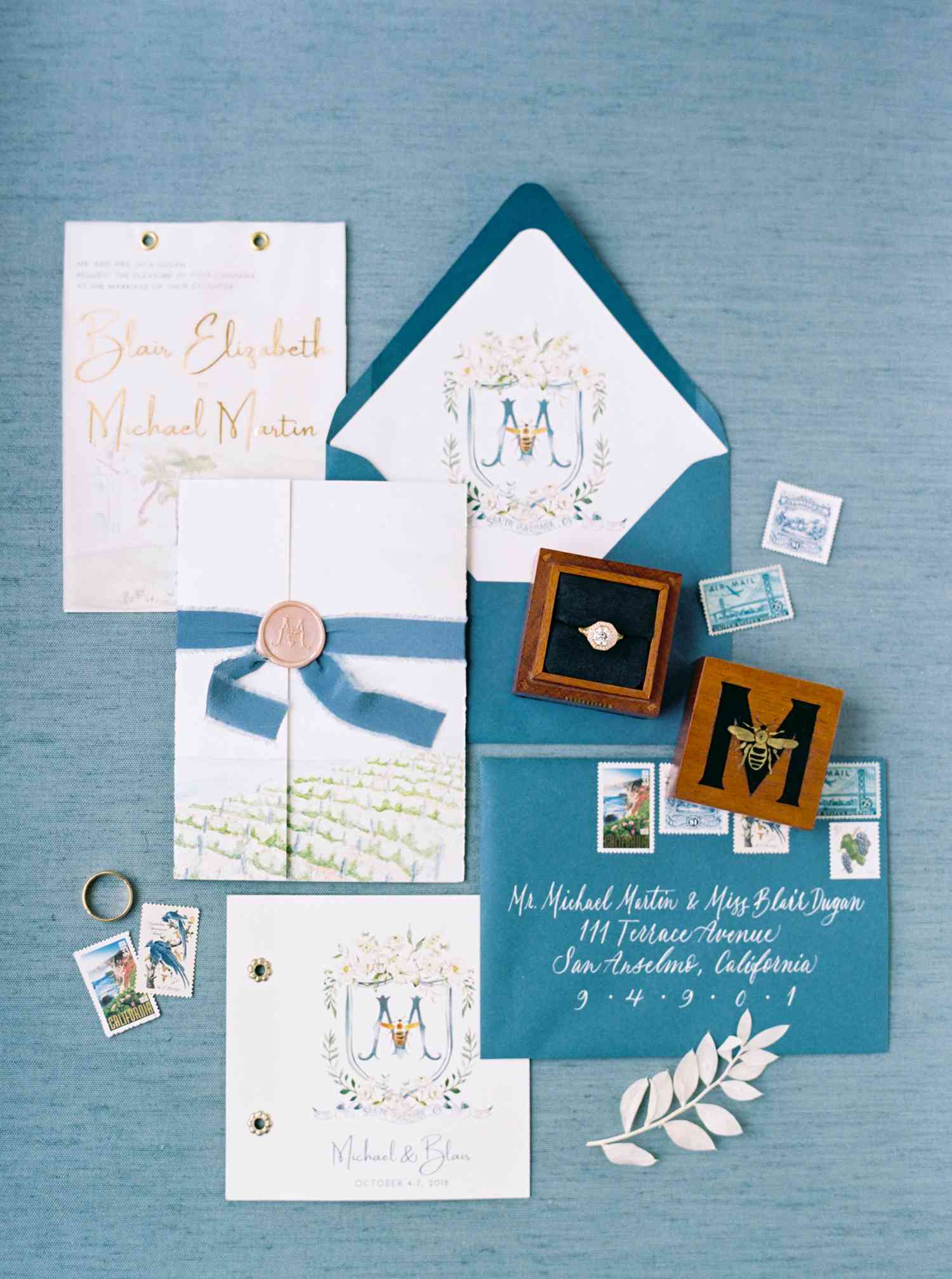Blue and white invitation suite with a custom on the envelope liner and insert, a wax-sealed invitation tied with blue ribbon, and watercolor details