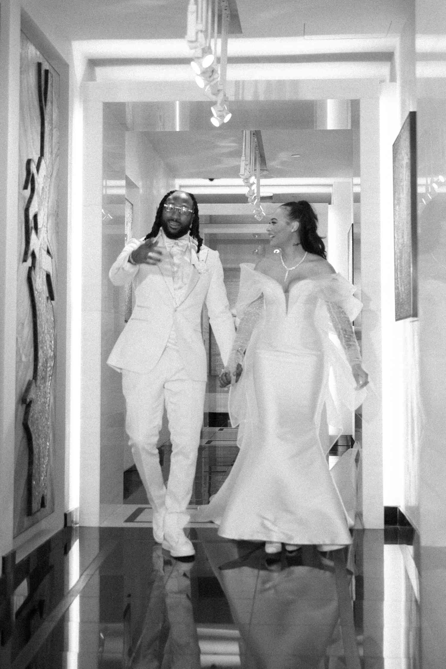 black and white couple portrait of bride and groom walking down a marble hallway