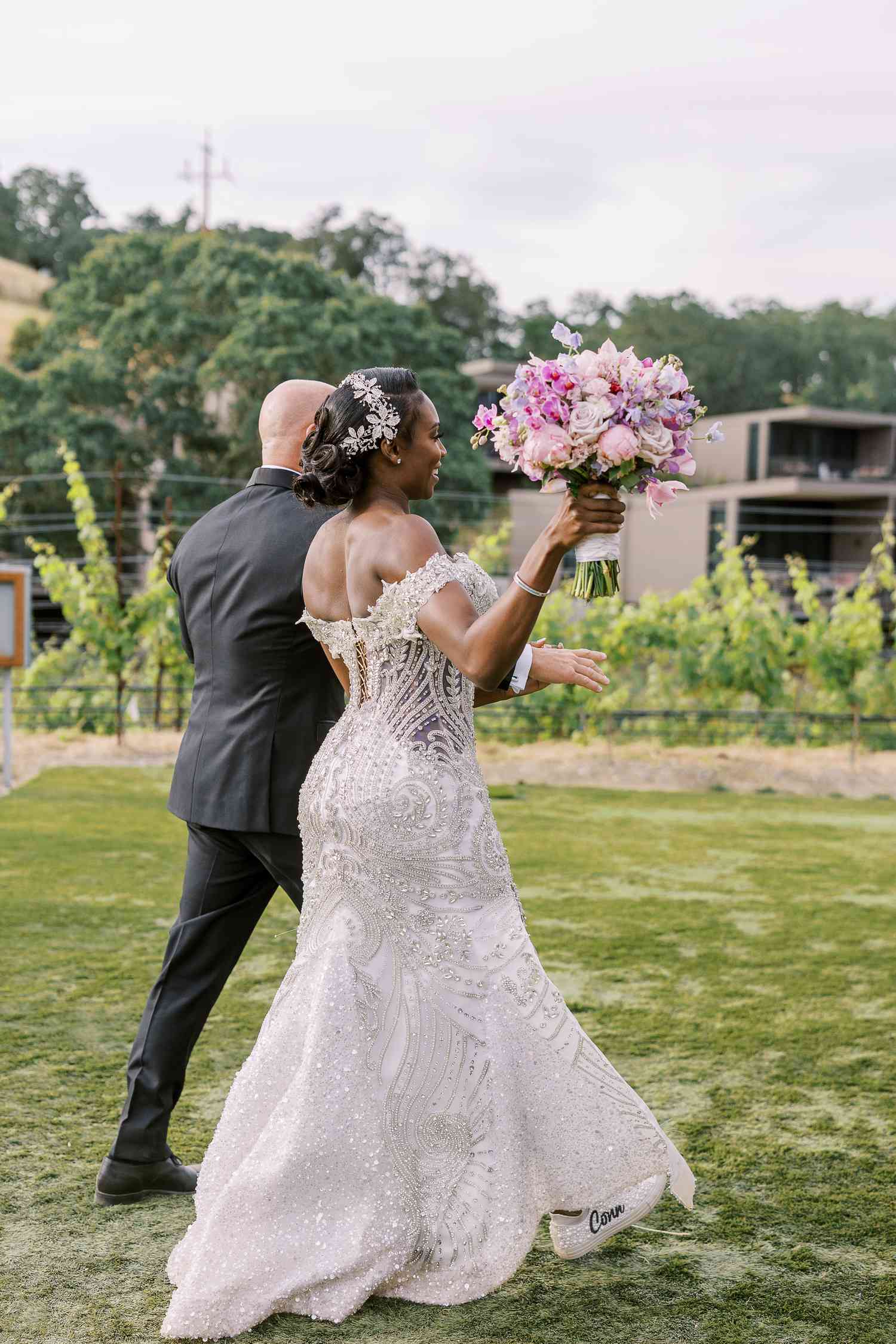 A Bride and Groom Make Their Wedding Entrance While the Bride Holds a Pink Bouquet in the Air