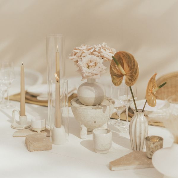 Wedding Reception Table With Beige Taper Candles, Cream Ceramic Vases With Anthurium and Roses, and Jagged Stones