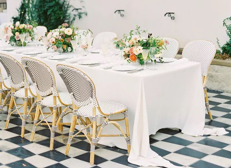 Wedding reception set up with white tablecloths, colorful floral centerpieces, and rattan chairs at Hotel Figueroa