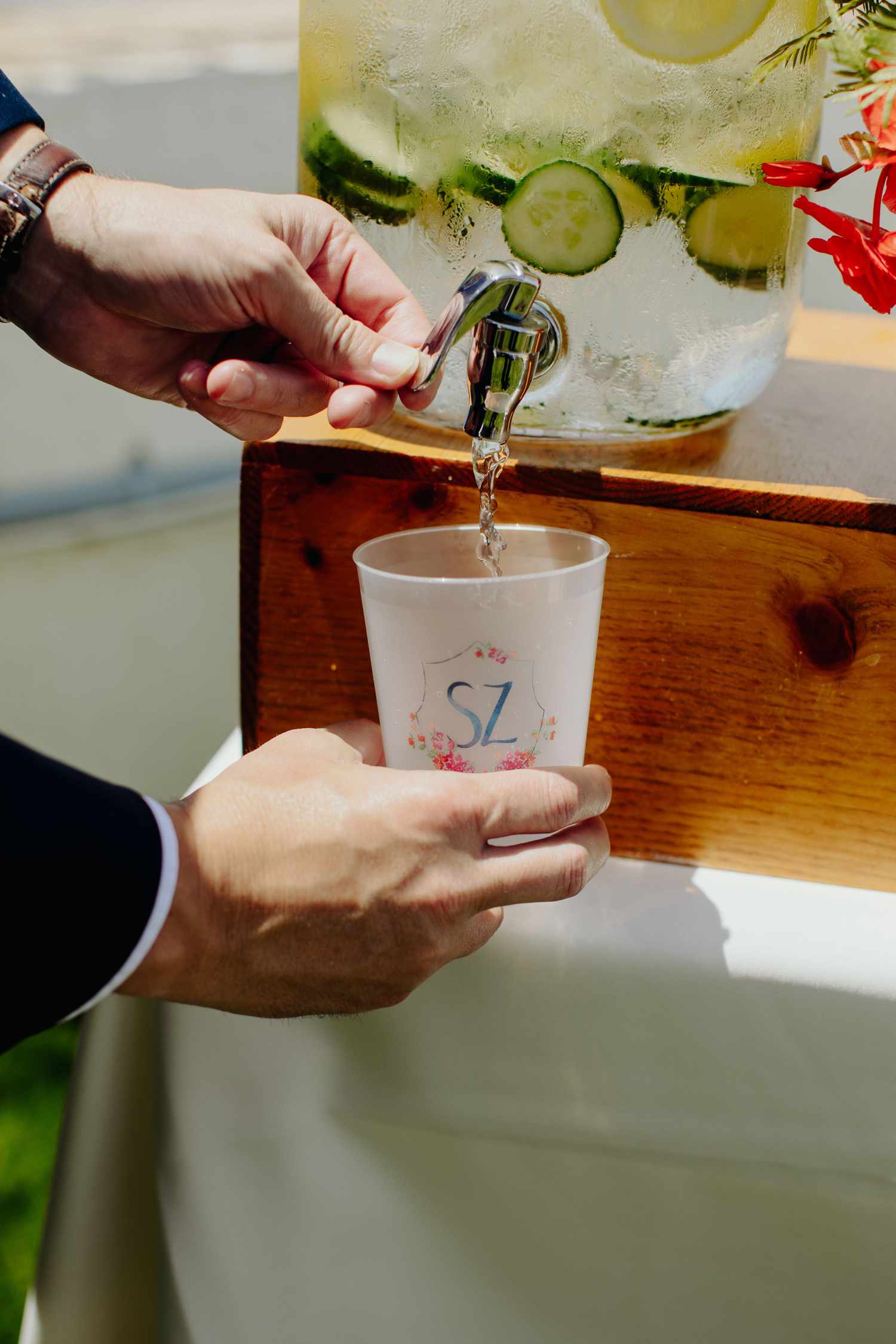 cucumber lemon water in a dispenser being served in custom plastic cup with illustrated crest