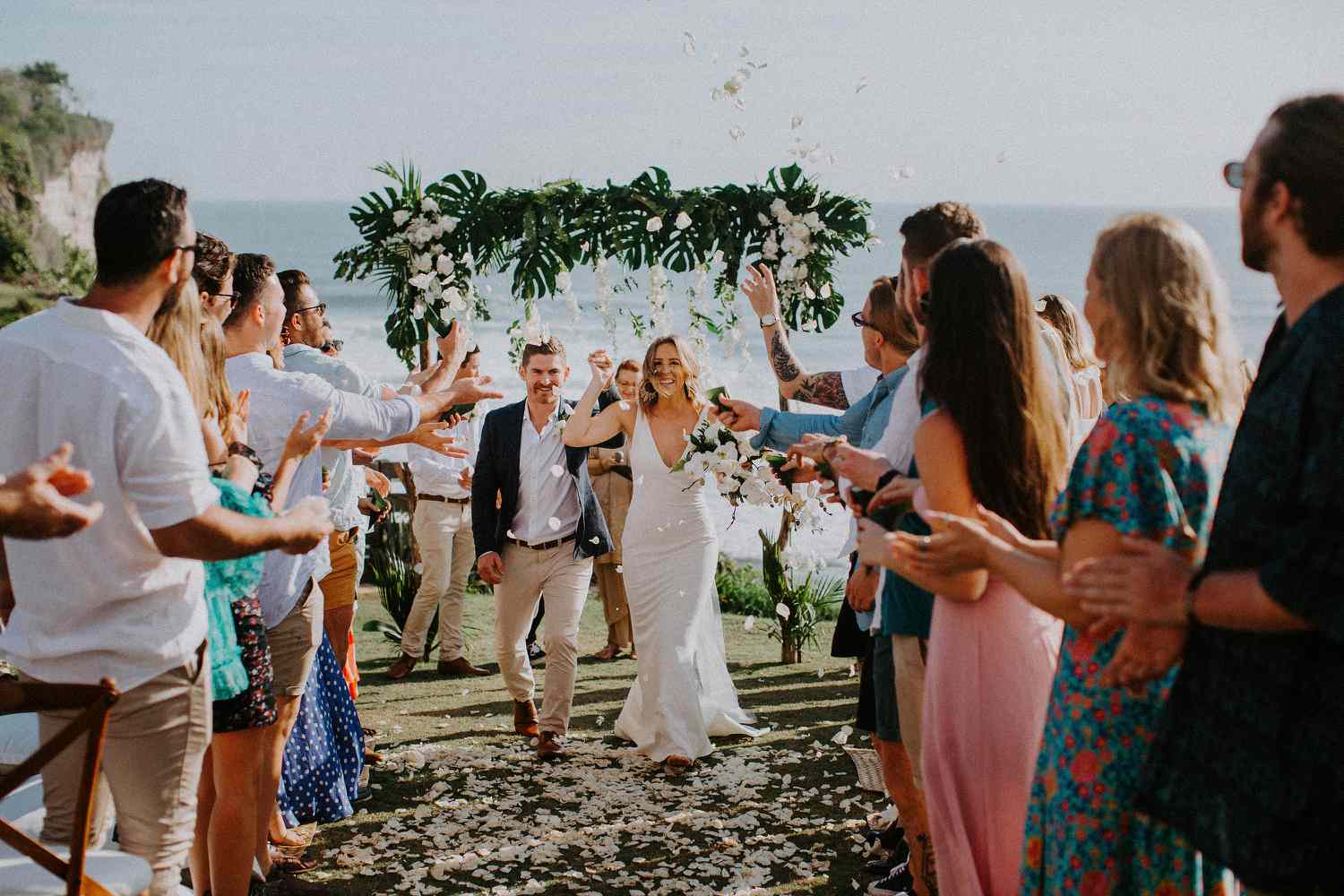 Bride and groom walk down the aisle after wedding ceremony on cliff by the ocean in Bali