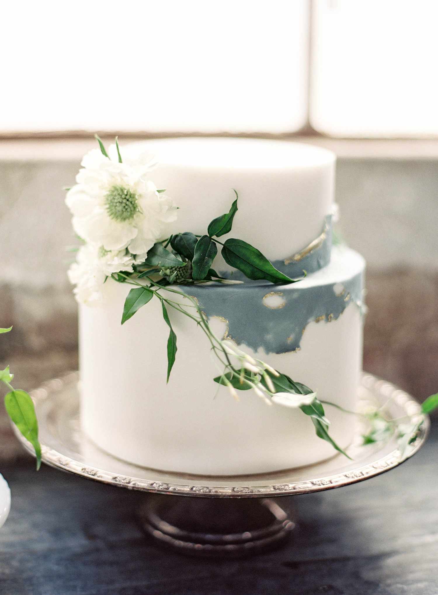 Two tier marbled blue, gold, and white cake with white florals