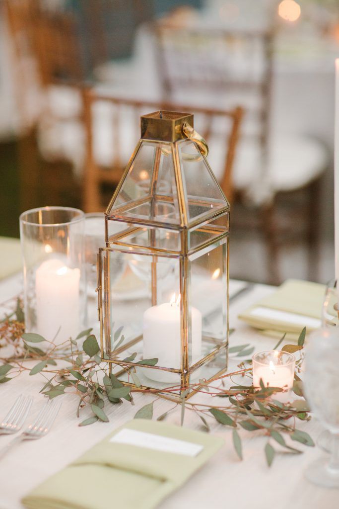 simple gold lantern with minimal greenery on a white tablecloth