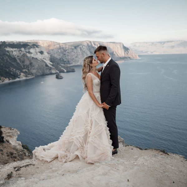 A beautiful bride and groom on their wedding day walk along the rocky coast by the sea
