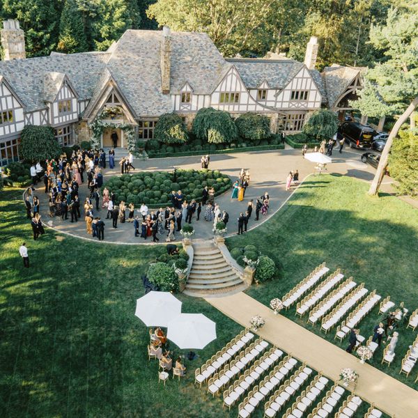 Wedding Guests Mingling on Driveway in Front of Beautiful Home with Wedding Ceremony on Front Lawn