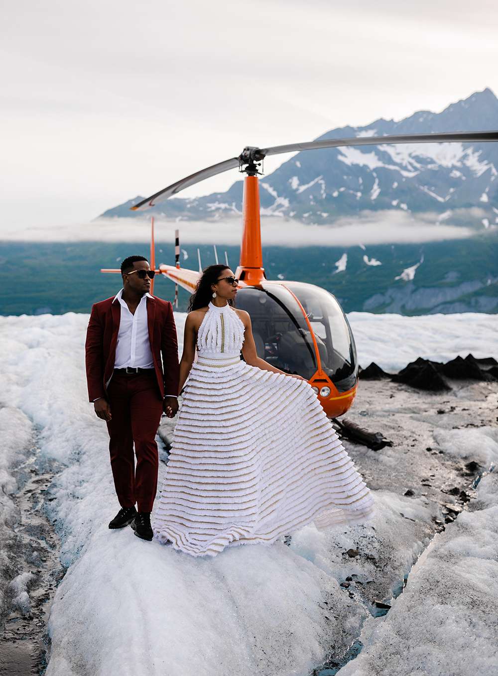 Couple Stands in Front of a Helicopter on an Alaskan Mountain During Their Destination Elopement
