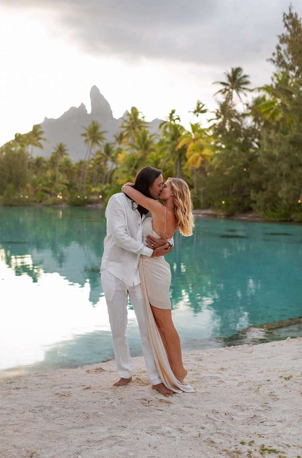 Couple Kisses During Their Destination Elopement in Bora Bora in Front of Palm Trees and Water