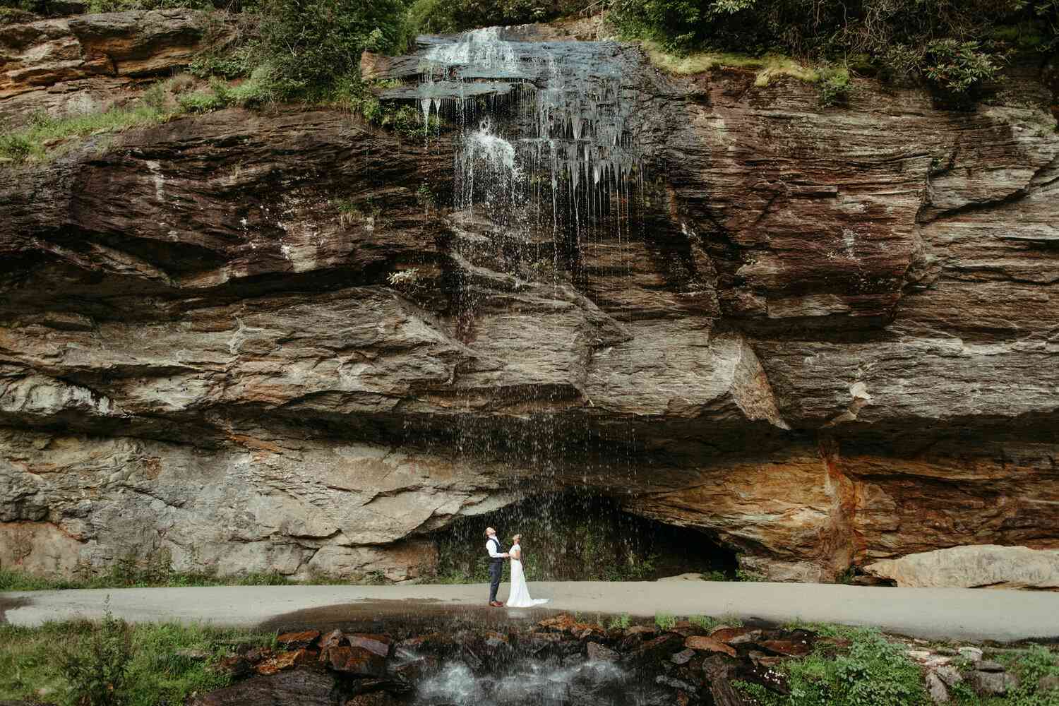 Couple Poses Under a Waterfall in Highlands, North Carolina During Their Destination Elopement
