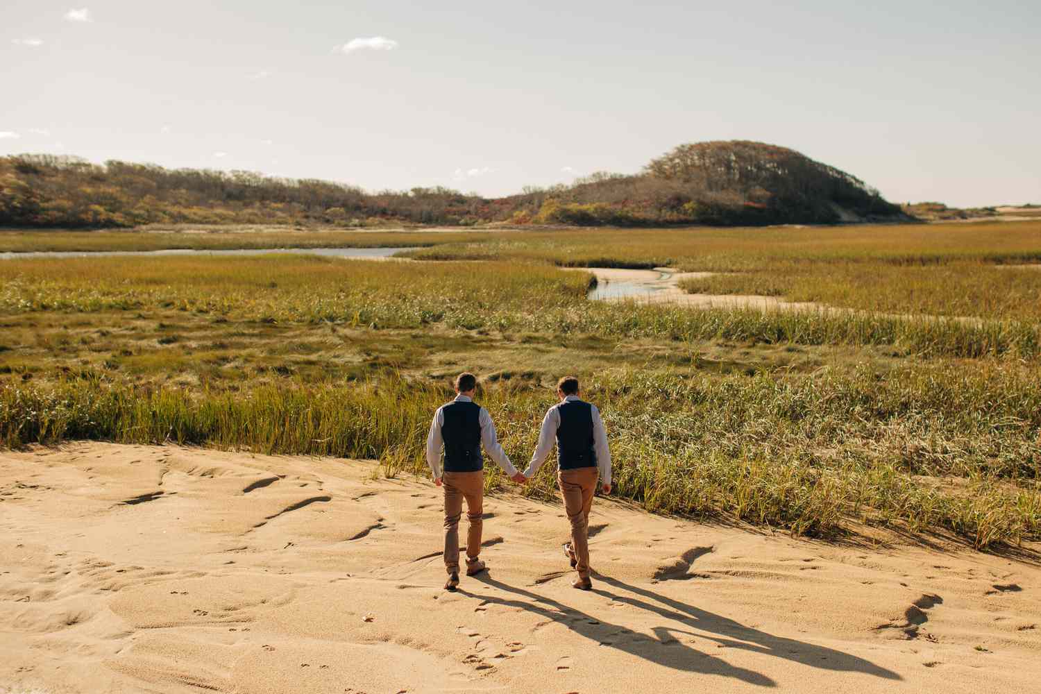 Couple Holds Hands While Walking on The Beach During a Destination Elopement in Provincetown, Cape Cod