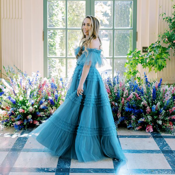 woman wearing a blue dress while posing in front of blue and pink flowers