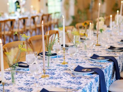 Rehearsal Dinner Venue with Tables Topped with Blue and White Linens, Taper Candles, and Simple Bud Vase Centerpieces