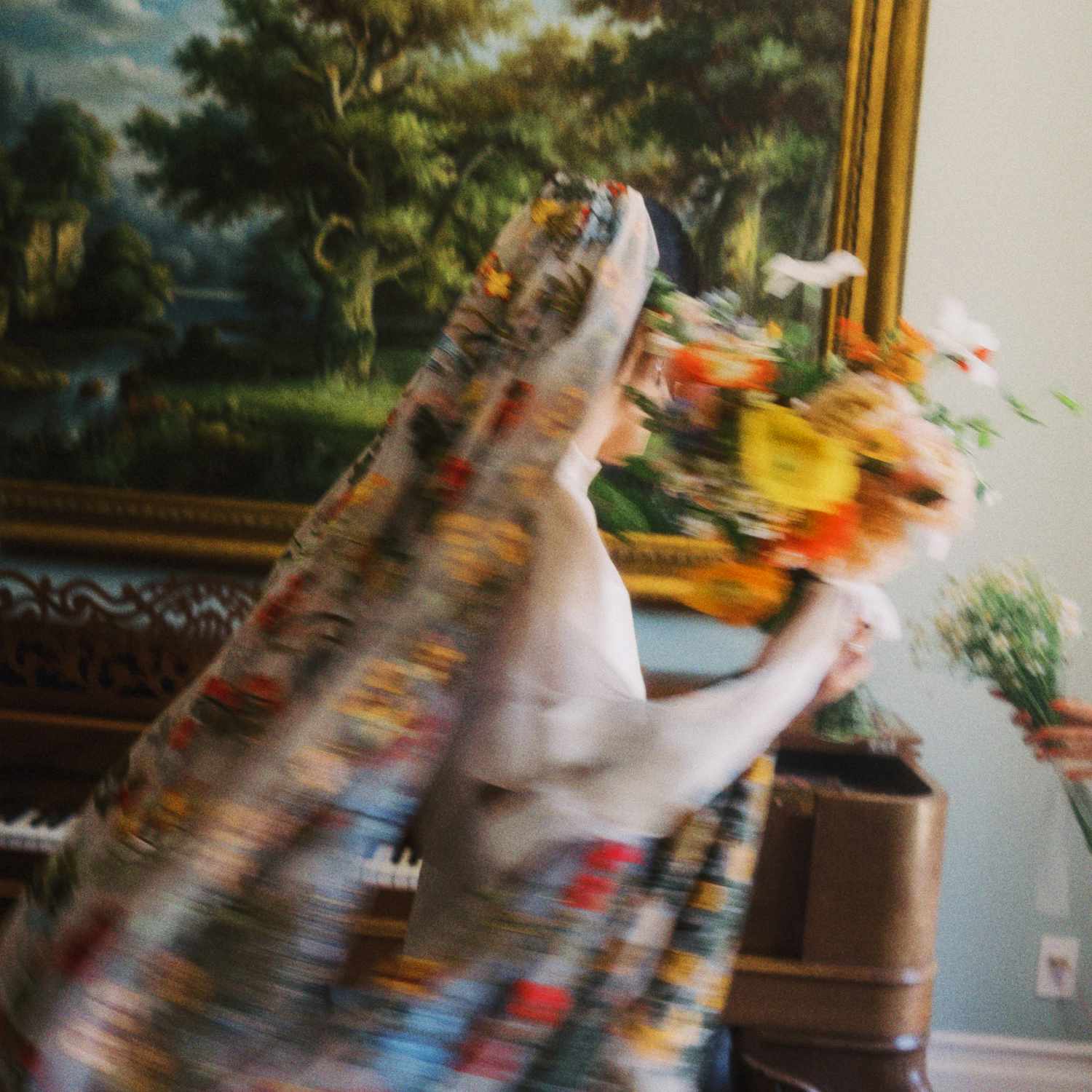 Blurry Photo of Bride Wearing Colorful Veil and Holding Bright Bouquet