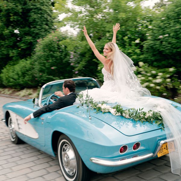 Bride Sitting on Top of Getaway Car While Groom in Tuxedo Drives