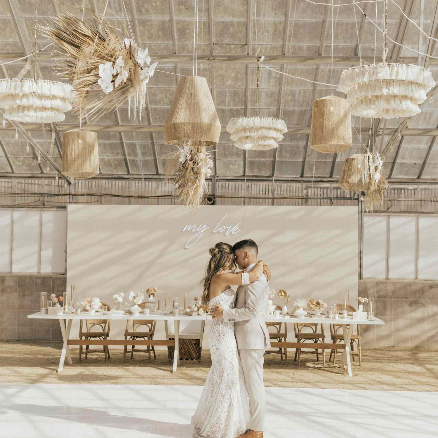 Bride and Groom Dancing on White Dance Floor With Rattan Lanterns Above Them