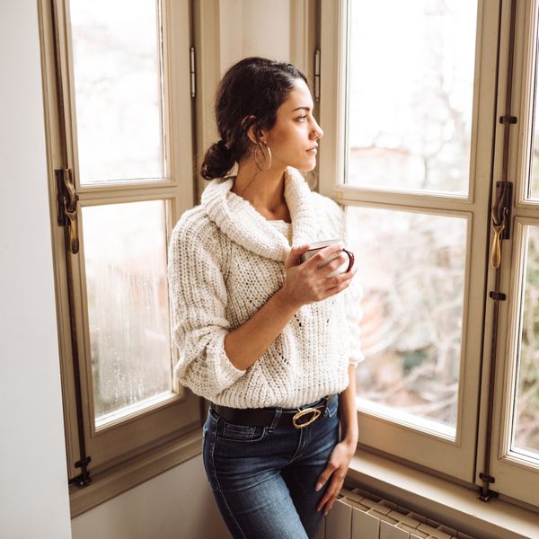 sad woman at home looking out the window