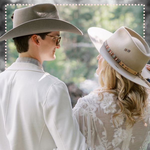 Brides couple wearing cowboy hats looking at eachother