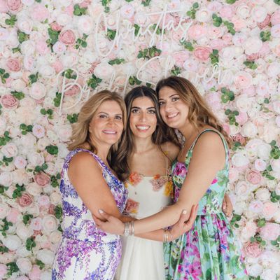 Bride with Mom and Sister Against Floral Wall with Neon Bridal Shower Sign