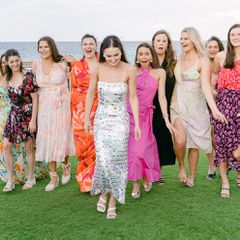 a group of women wearing colorful dresses walking and smiling