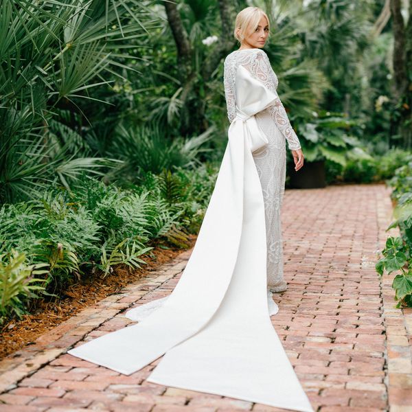 a bride wearing a long-sleeve lace wedding dress with an oversized back bow