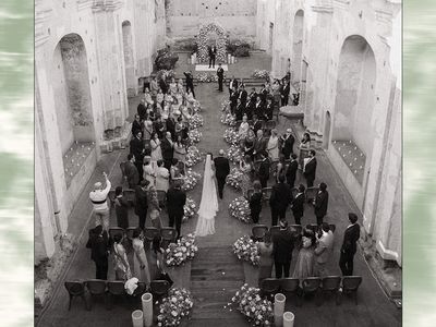 wedding ceremony processional in old castle with flower-lined aisle