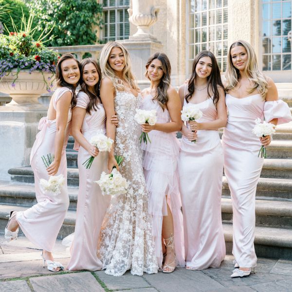 bride posing with her bridesmaids who are wearing light pink mismatched dresses