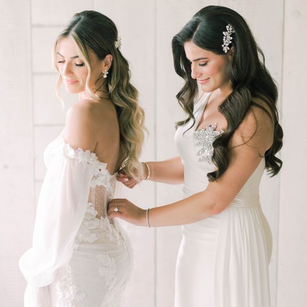 bridesmaid zipping up the back of a bride's dress