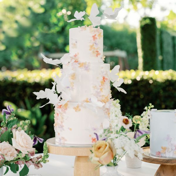 three-tier wedding cake decorated with flowers and butterfly motifs