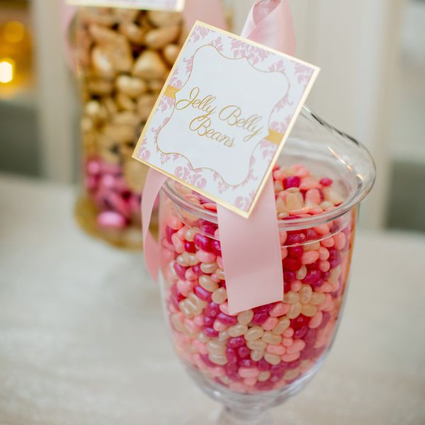 a jar of pink, red, and gold jelly beans at a wedding candy bar