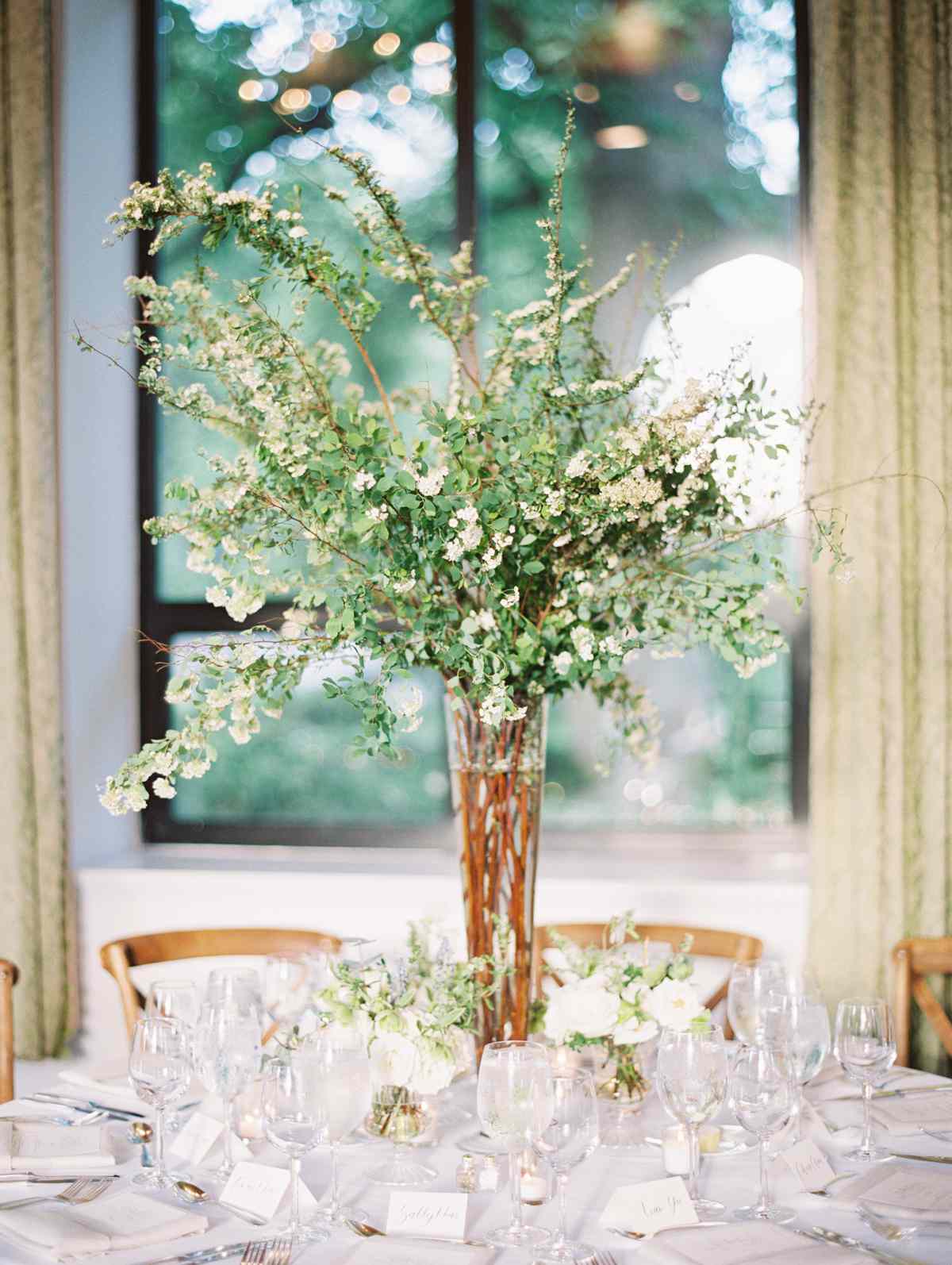Glass Vase With Tall Arrangement of Greenery in the Middle of Round Table