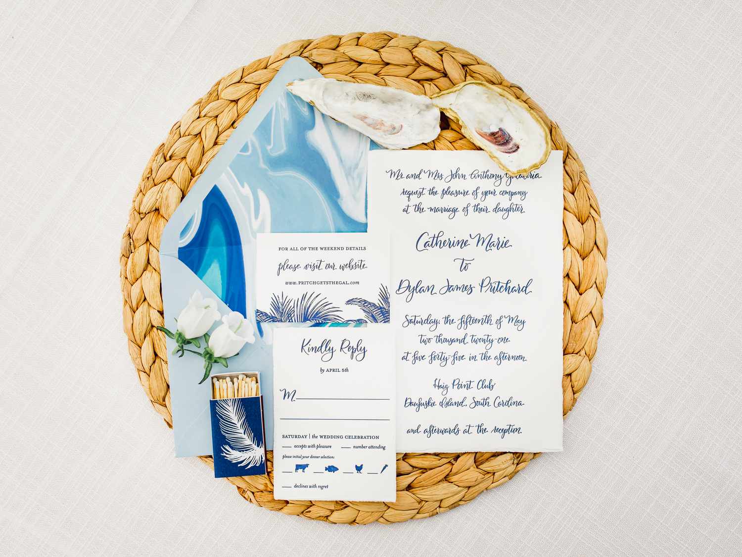 Blue-and-white invitation suite with designed marble liner inspired by the sea, shells, and feather accents