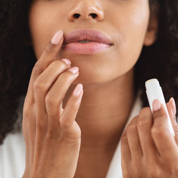 Close-up shot of a woman's lips as she applies chapstick with her finger